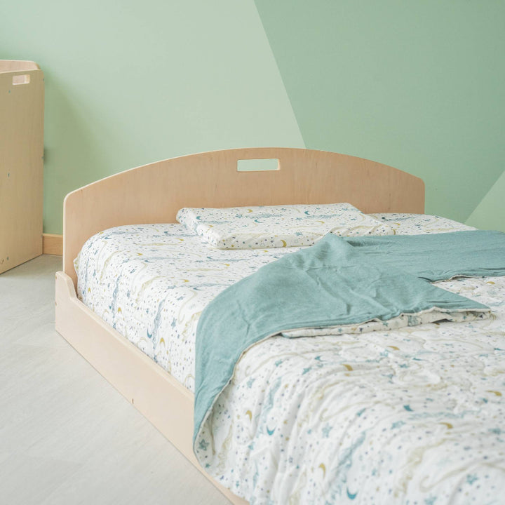 Second lifestyle view of the Sapiens Child Cherry Montessori floor bed in a children's bedroom, showing the compact shelf-free Canadian-made twin frame