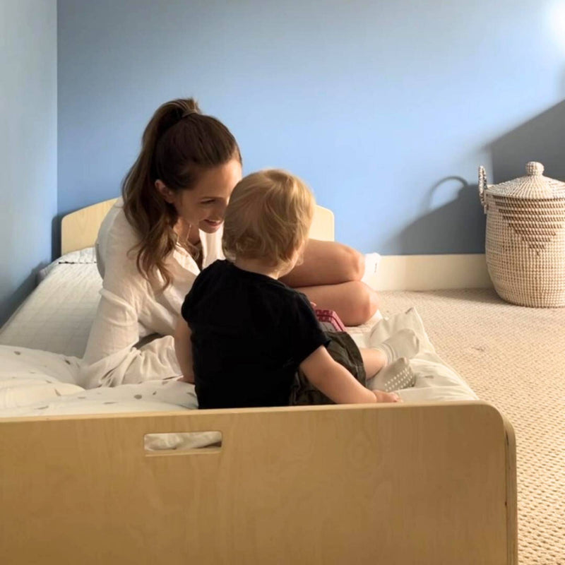 Parent and child together on the Sapiens Child Cherry Montessori floor bed, showing the low-profile design that makes co-reading and connection at floor level natural