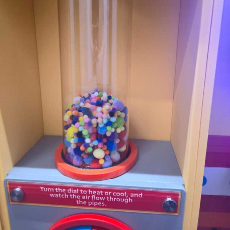 Close view of the LiteZilla PomPom Cyclone sensory air tube packed with multicoloured pom poms resting at the base of the clear tube