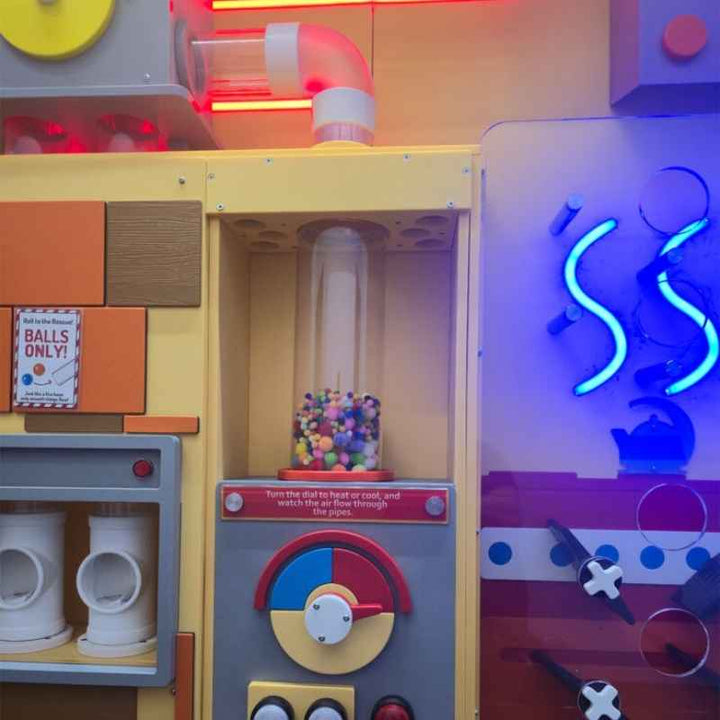 LiteZilla PomPom Cyclone sensory air tube installed alongside other interactive exhibits, showing the connecting air pipe and control panel