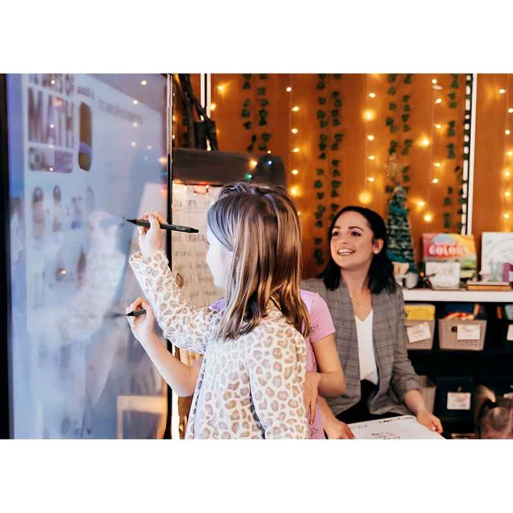 Two children using the SMART Board GX Plus interactive whiteboard with adult supervision, demonstrating multi-touch collaborative learning in an educational setting