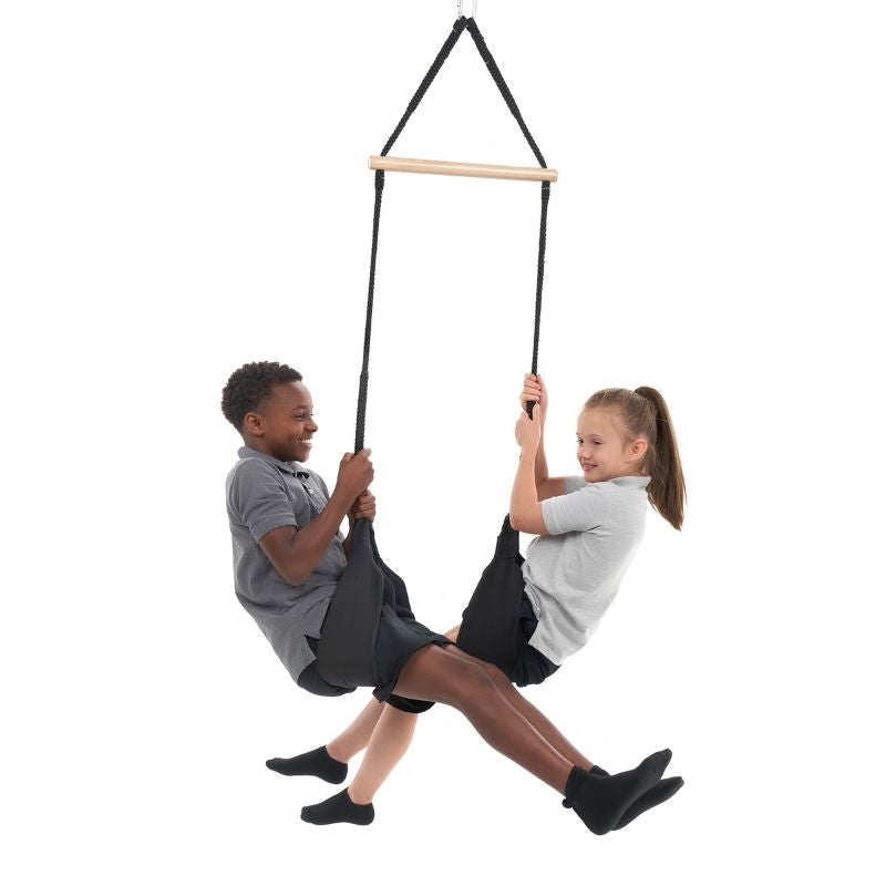 Two children swinging together on the Southpaw Interaction Dual Swing, a two-person vestibular therapy swing for sensory integration and OT clinic use