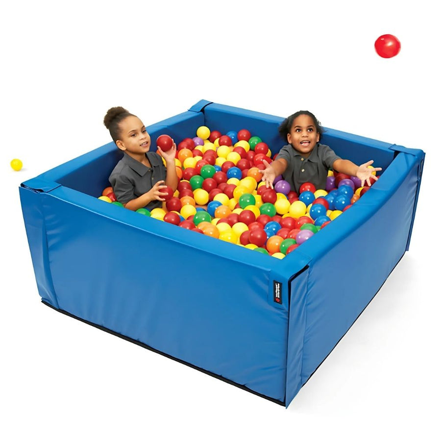 Two children playing inside the Southpaw Mini Crash Pit in blue, a compact sensory foam pit for deep pressure input and active play