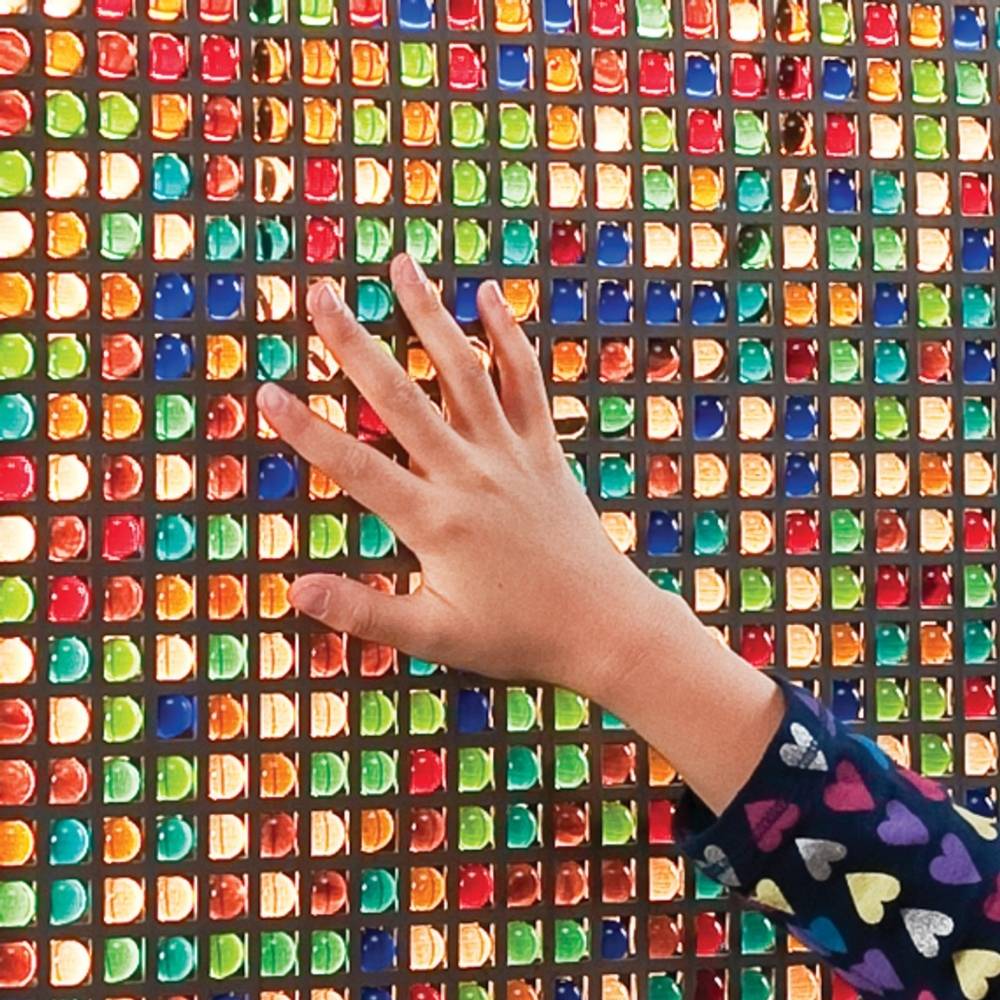Close-up of a hand interacting with the Southpaw Mini Marble Panel, showing the tactile sensory marble surface and fine motor engagement