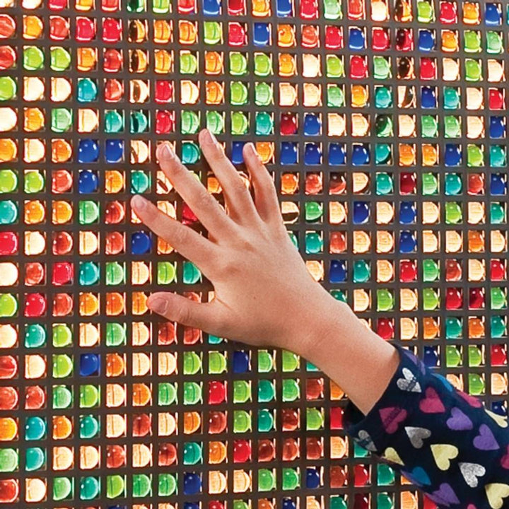 Close-up of a hand interacting with the Southpaw Mini Marble Panel, showing the tactile sensory marble surface and fine motor engagement