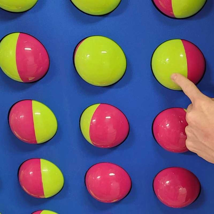 Close-up of a hand rotating a bi-colour sphere on the LiteZilla Spinfinity Wall interactive spinning wall panel