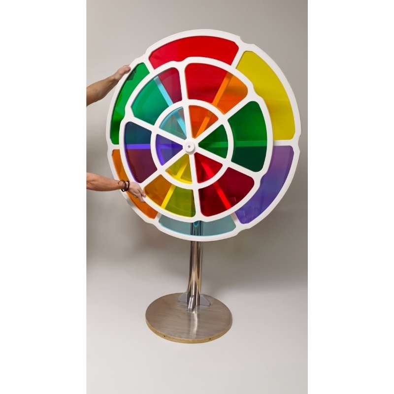 Two hands positioning the full LiteZilla ChromaWheel on its stand, an interactive color wheel built for STEM and sensory spaces
