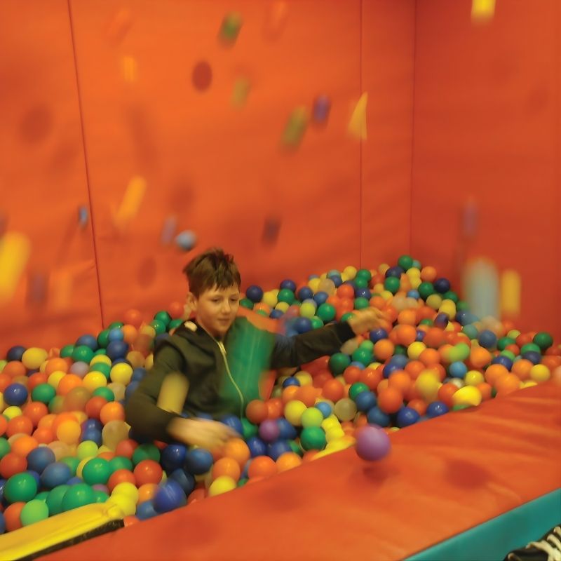Child playing in a sensory ball pit filled with TFH 1000 mixed colour ball pool balls, demonstrating proprioceptive sensory play