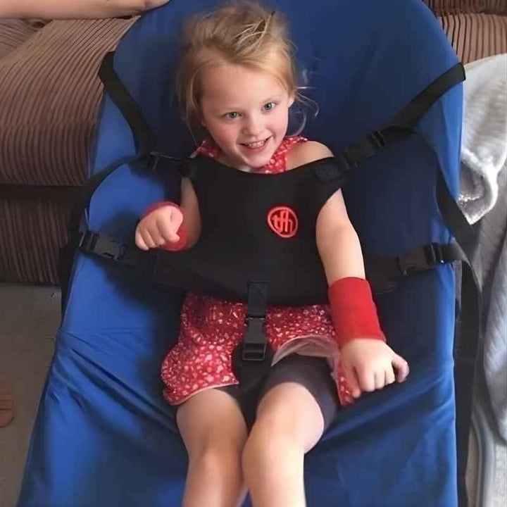 Child sitting happily in the TFH Bouncing Chair medium dark blue variant, demonstrating vestibular sensory seating for focus and self-regulation