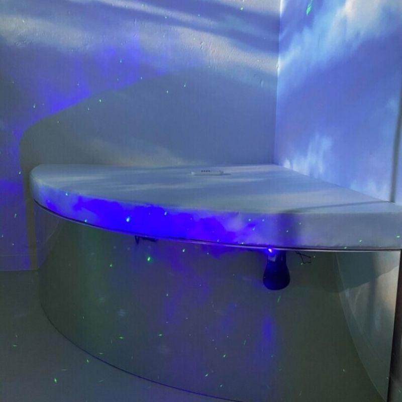 Close-up of the TFH Bubble Tube Corner Seat Base podium showing the padded vinyl cushion surface and mirrored acrylic base