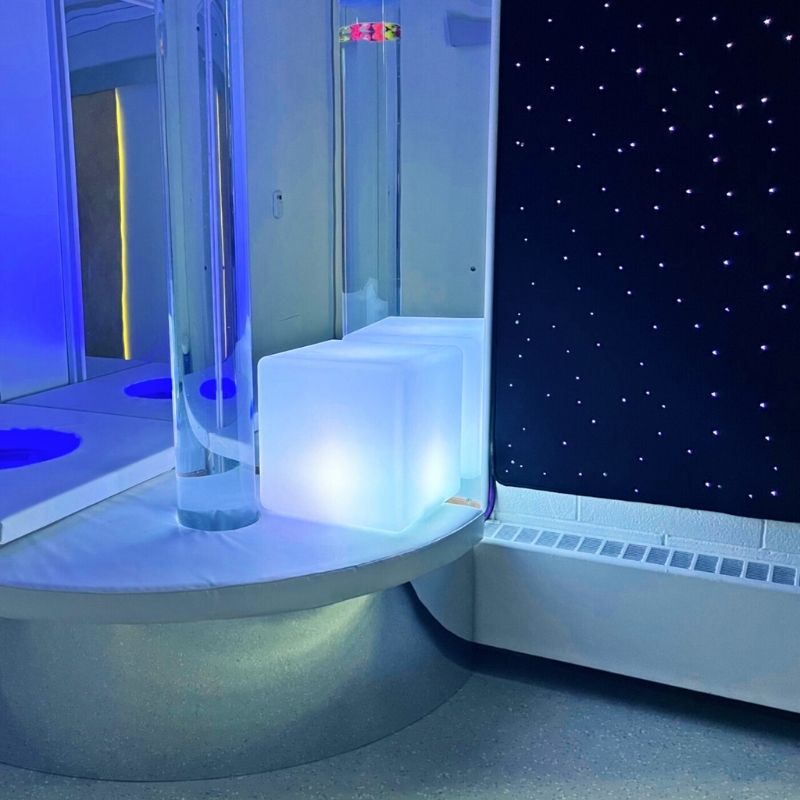TFH Bubble Tube Corner Seat Base installed in a sensory room corner, showing the padded mirrored podium with bubble tube in place