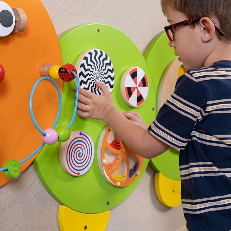 Child engaged with the TFH Caterpillar Activity Wall Panel, practising fine motor skills and hand-eye coordination on the wall-mounted sensory busy board