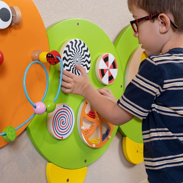 Child engaged with the TFH Caterpillar Activity Wall Panel, practising fine motor skills and hand-eye coordination on the wall-mounted sensory busy board