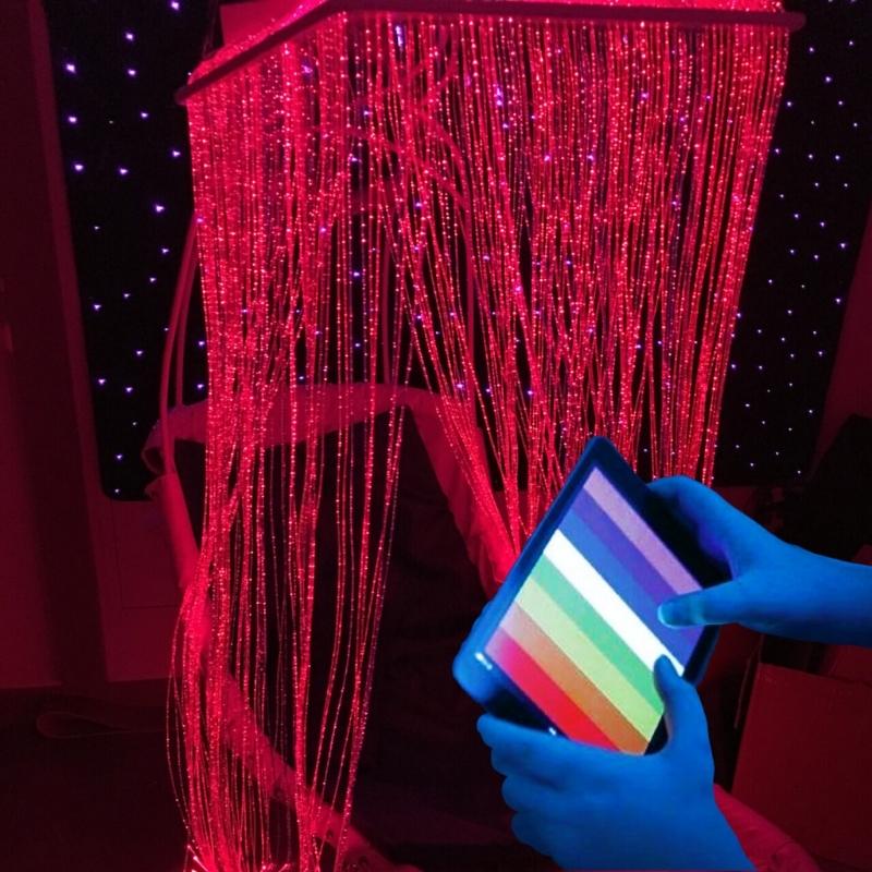 TFH Fibre Optic Waterfall Genie Controlled System in a sensory room with red fibre optic tails and a user holding the MSE Genie App colour controller on a smartphone