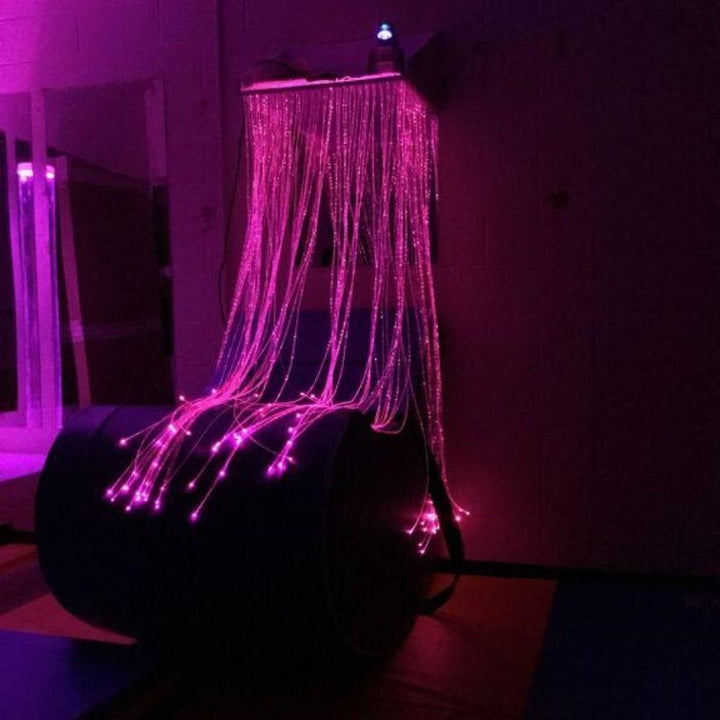 TFH Fibre Optic Waterfall in a landscape sensory room view with tails glowing in soft pink, demonstrating the colour-changing fibre optic light for visual sensory stimulation