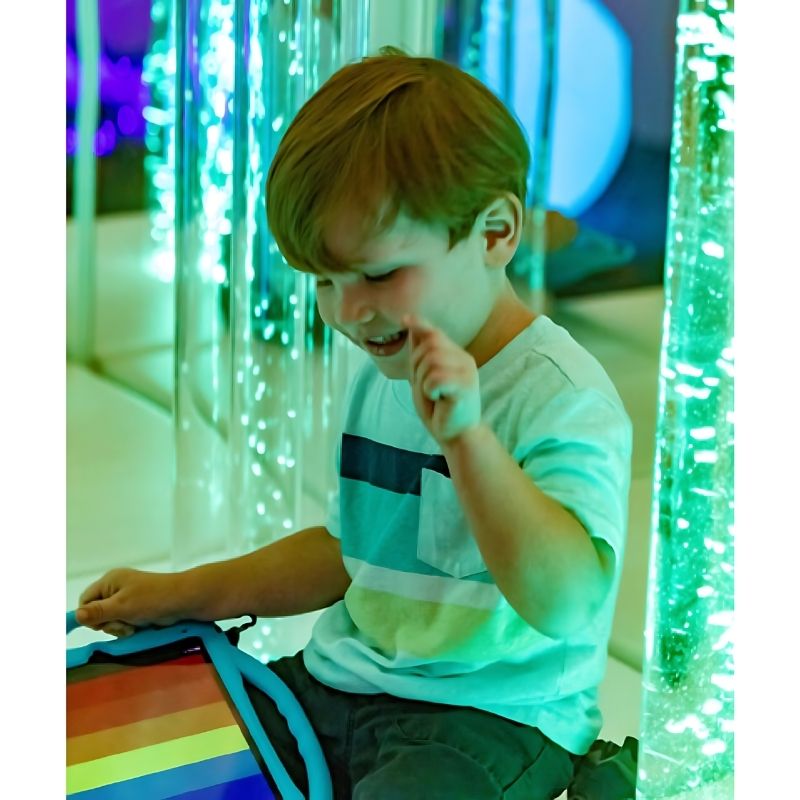 Child actively engaging with the TFH Genie System Bubble Tube during sensory room play, demonstrating visual tracking and colour stimulation