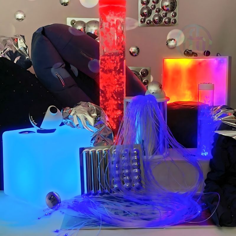 TFH Sensory Room Kit Immersive Package displayed in reddish ambient lighting showing the complete multi-sensory room environment with bubble tube and fibre optic elements