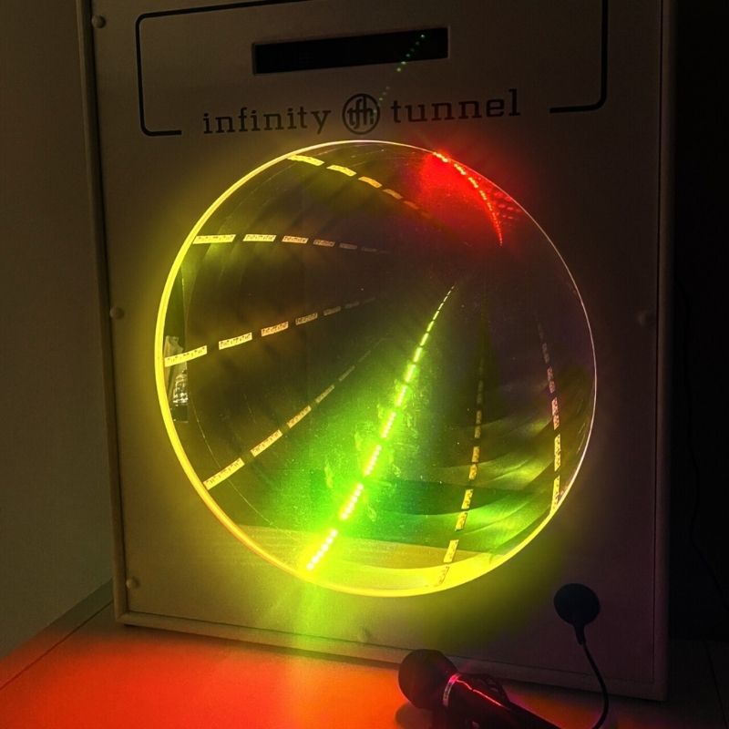 TFH Interactive Infinity Tunnel and Microphone front view glowing in golden light, showing the optical illusion of infinite depth created by the sound-responsive LED sensory wall panel
