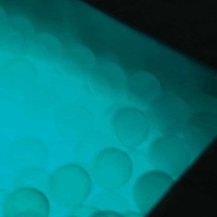 Close-up of TFH Large Light-Up Ball Pit translucent sensory balls in Aruba blue LED light for calming visual stimulation