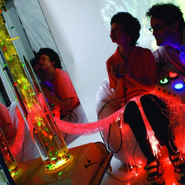 Man and woman interacting with the TFH Mobile Sensory Cart Deluxe fibre optic tails glowing red during a sensory therapy session