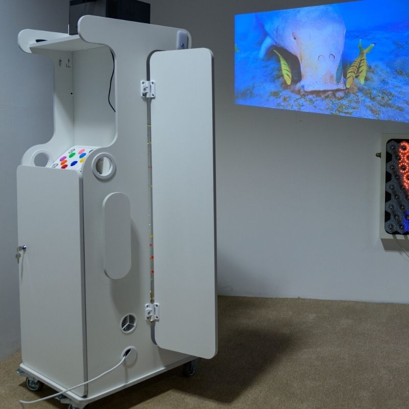 Side view of the TFH Mobile Sensory Cart Deluxe showing marine MDF construction, acrylic mirror wing, locking caster wheels, and full cart profile