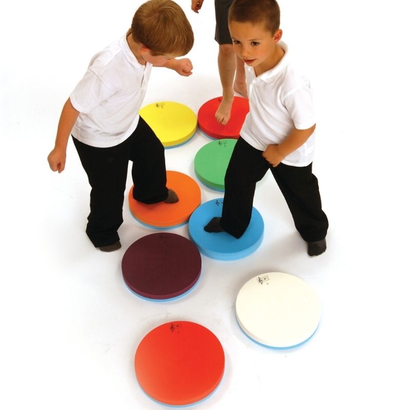 Children actively playing with TFH Musical Stepping Notes, stepping and jumping on the colour-coded acoustic pads to create musical notes