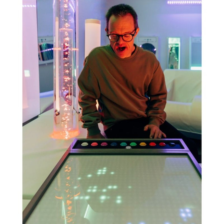 Adult using the TFH Pixels Pro interactive sensory light panel during a therapy session, demonstrating switch-adapted control