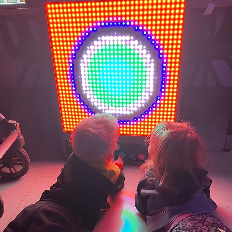 Two children actively using the TFH Pixels Pro Illumination Panel, building colour patterns in Circle Grow and Fireworks modes