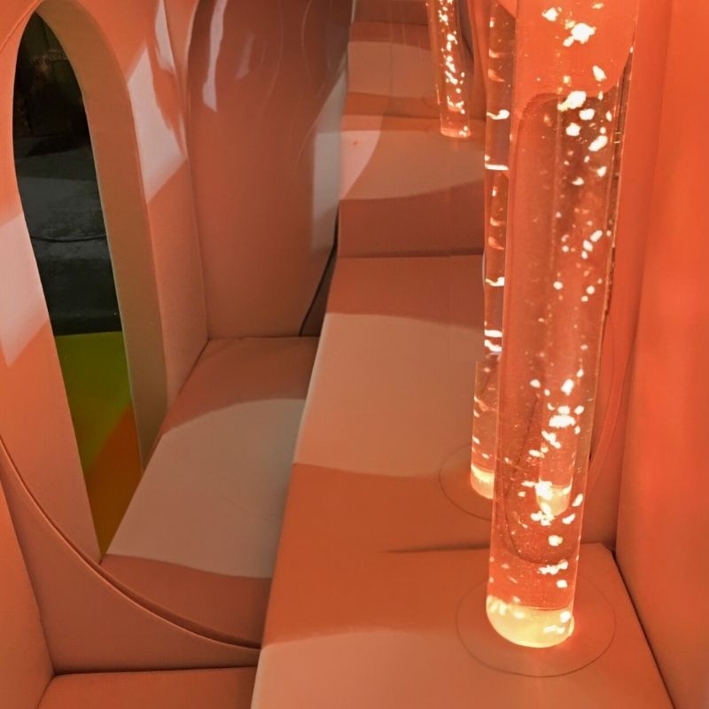 TFH Deluxe Portable Sensory Den with bubble tube glowing in orange light, showing the soft-sided fold-flat sensory enclosure with colour-changing bubble tube inside for calm corners in classrooms and therapy rooms