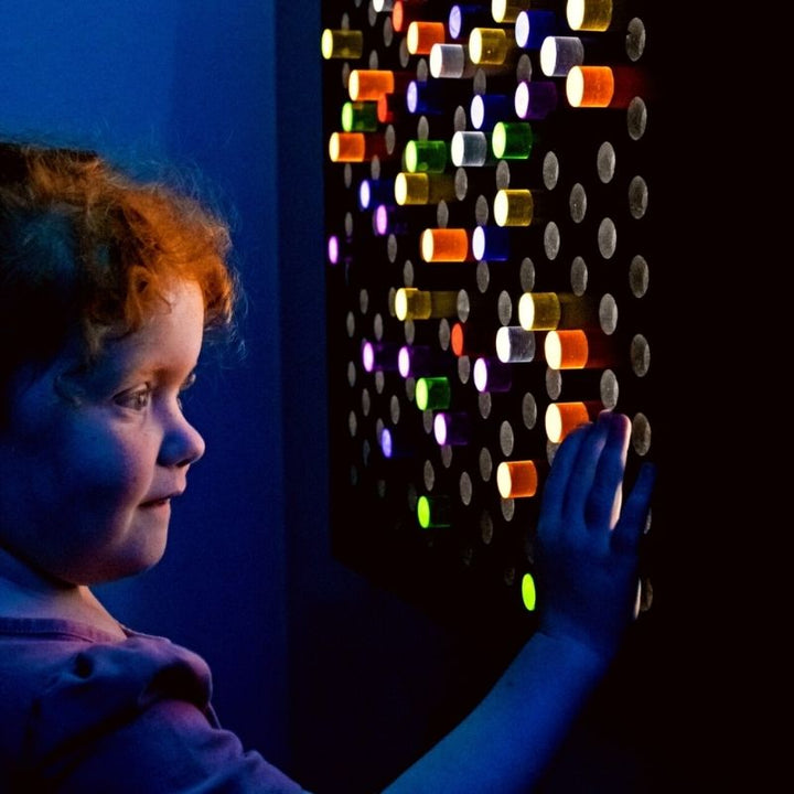 TFH Rod Wall Activity Panel with a child engaging from the side, showing the illuminated 144-rod panel in use as a fine motor and visual sensory therapy tool in a sensory room