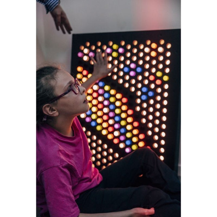 TFH Rod Wall Activity Panel with a child actively touching and manipulating the coloured rods, demonstrating fine motor and tactile sensory engagement with the dimmable LED peg panel