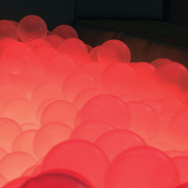 Close-up of TFH Large Light-Up Ball Pit translucent balls glowing in red LED light demonstrating 16-colour light cycle
