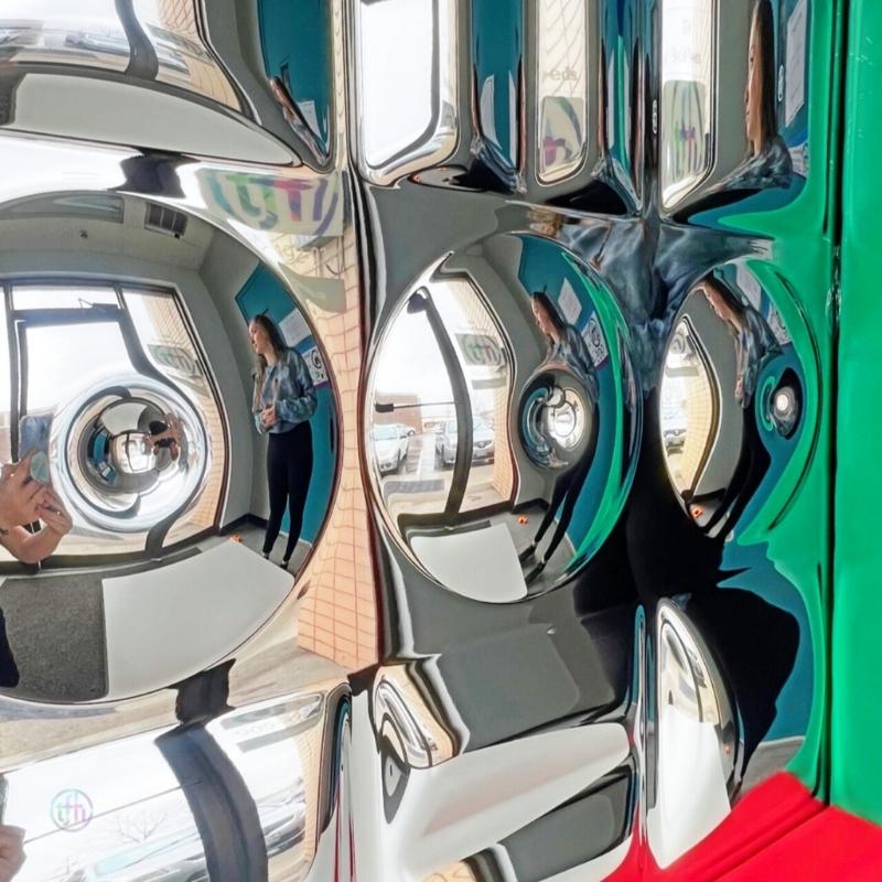Adult reflected in the TFH Sensory Mirror With Padded Frame, showing the convex and concave distortion surfaces creating a funhouse mirror effect in a sensory or therapy space
