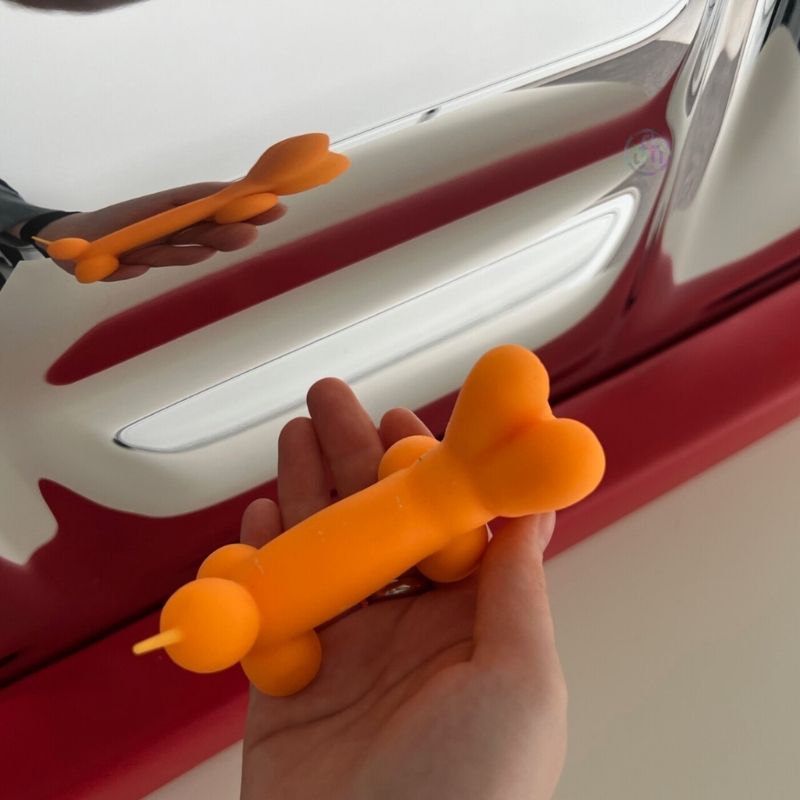 Hand holding an orange balloon reflected in the TFH Sensory Mirror With Padded Frame, demonstrating how objects appear distorted across the nine convex and concave mirror surfaces