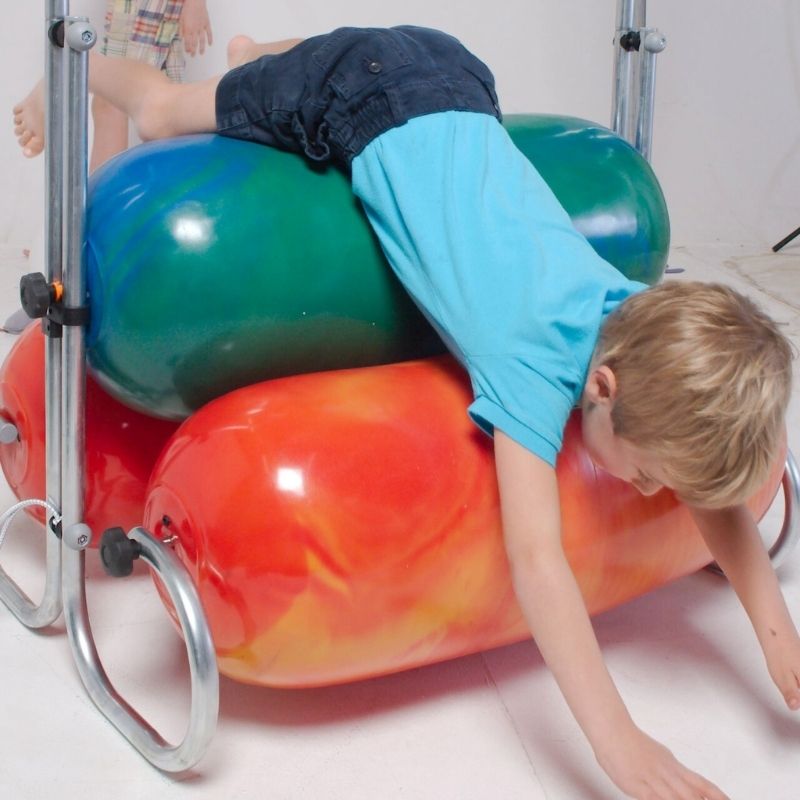 Toddler playing on top of the TFH Squeeze Machine, exploring deep pressure proprioceptive sensory input in a home or therapy room setting