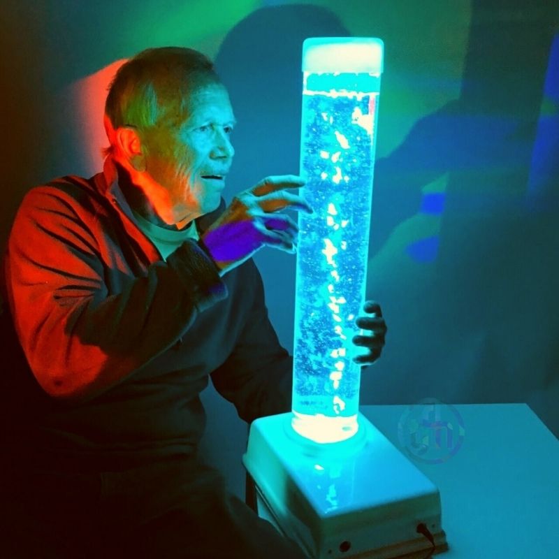 Adult watching the TFH Tabletop Bubble Tube Kit in a sensory setting, showing the portable 24" bubble tube delivering calming visual stimulation