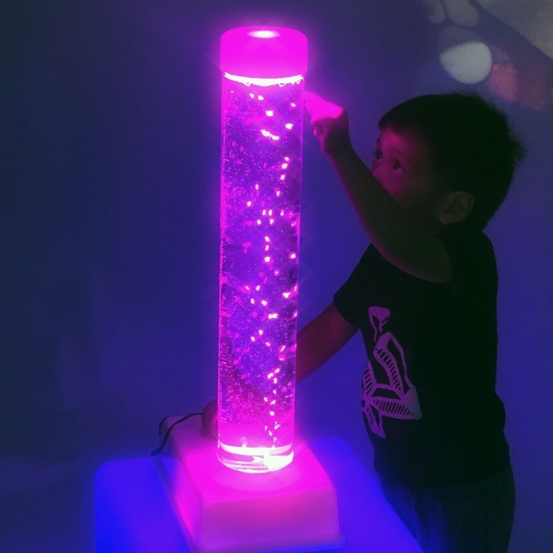 Child interacting with the TFH Tabletop Bubble Tube Kit in pink light, demonstrating tactile engagement with the portable sensory bubble tube