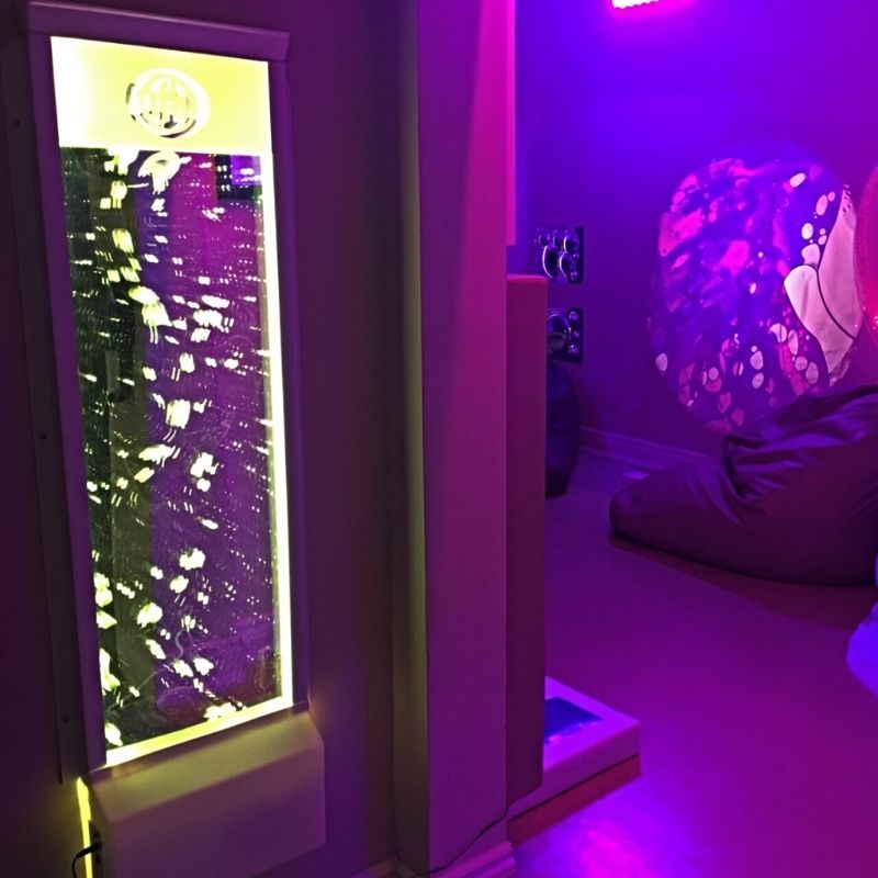 TFH Lights & Bubbles Water Panel wall-mounted in a sensory room with purple LED light, showing the full-room sensory bubble wall installation