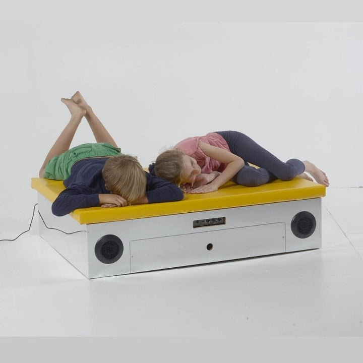 Two children using the TFH Vibroacoustic Platform with Foam Pad demonstrating full-body vibroacoustic sensory therapy and sound vibration input