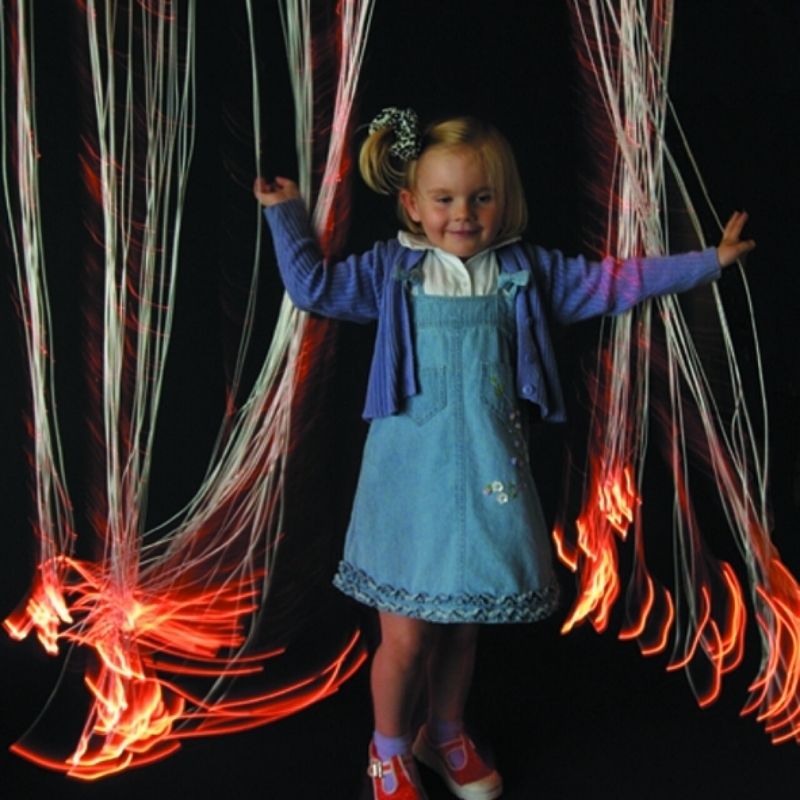 TFH Wall Mounted Fiber Optic Curtain with a child reaching into the glowing sensory light strands, showing tactile and visual stimulation in a home sensory space