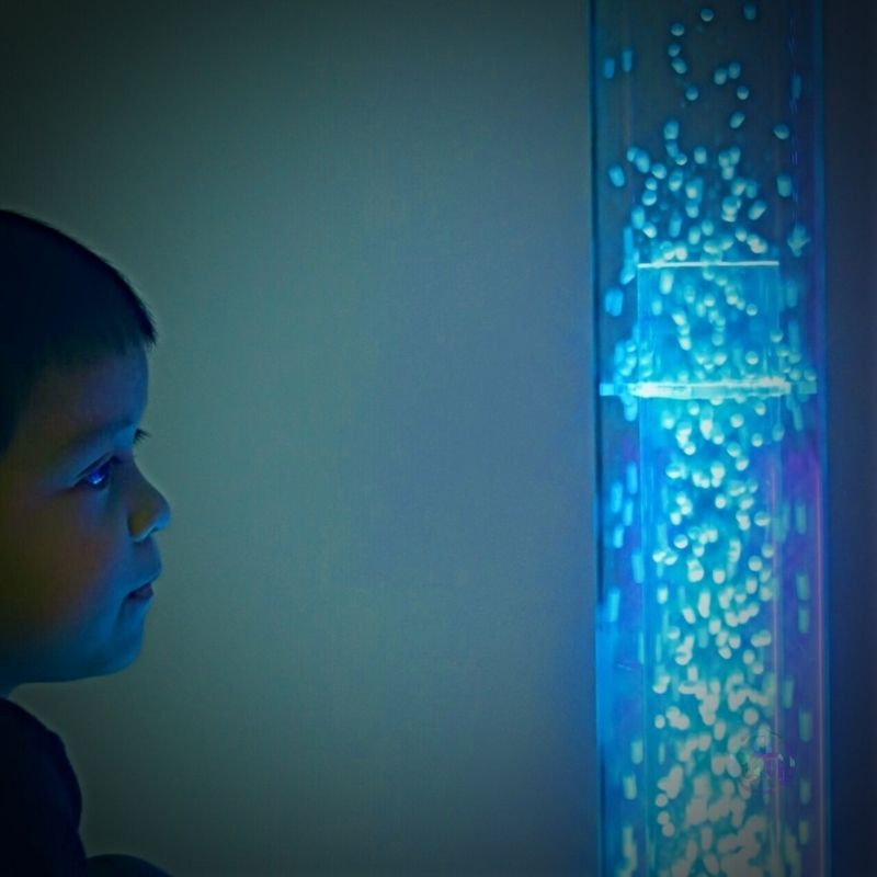 TFH Interactive Waterless Hurricane Tube with a child gazing at the swirling snow beads, demonstrating the visual focus and calming sensory engagement of the waterless bubble column