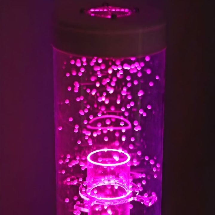 Close-up of the TFH Interactive Waterless Hurricane Tube in pink light showing the snow beads swirling inside the 6-inch acrylic column with LED colour-changing illumination