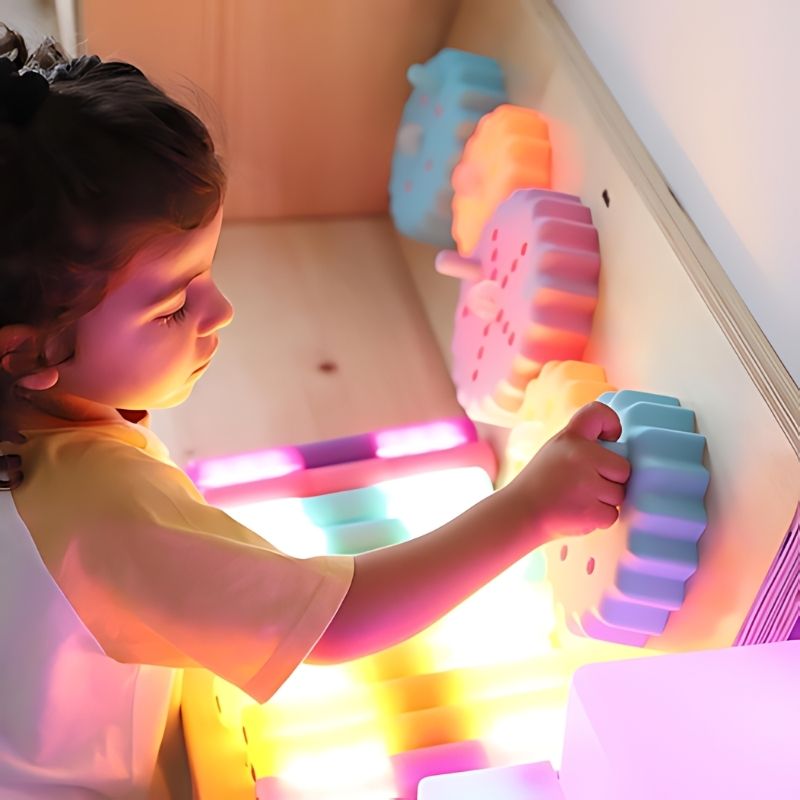 Close-up of a child's hands twisting the colour-changing cogs on the TTS Light Up Cog Board, building dexterity and cause-and-effect thinking