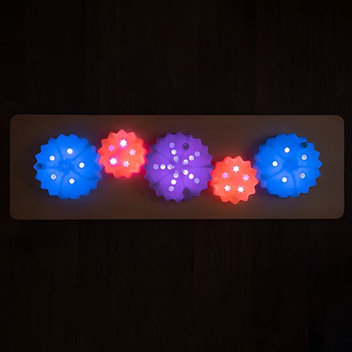 TTS Light Up Cog Board wall-mounted in a sensory room setting, suitable for occupational therapy and early years environments