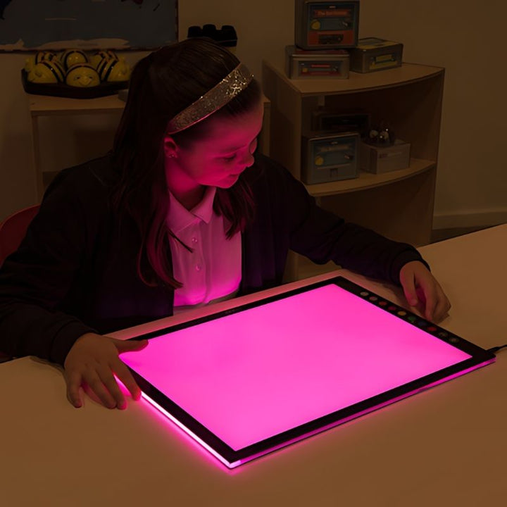 Girl exploring the TTS Colour Changing Light Panel in purple light mode, demonstrating multisensory visual stimulation in a home or classroom setting