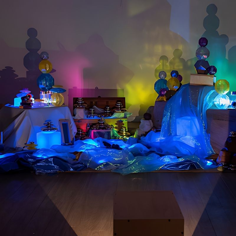 TTS Early Years Projector producing a large-scale colourful light and shadow display with loose parts and translucent objects across a full classroom or therapy room space