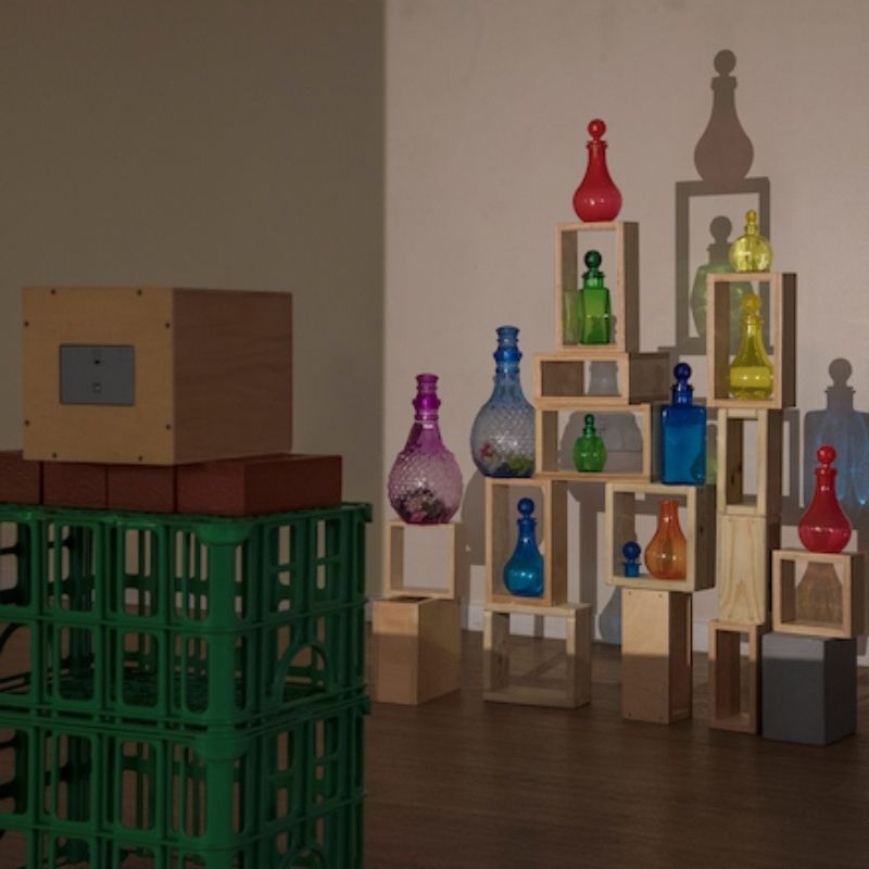 TTS Early Years Projector casting intricate shadow silhouettes of glass bottles and wooden blocks onto a wall, supporting creative arts, visual discrimination, and sensory exploration