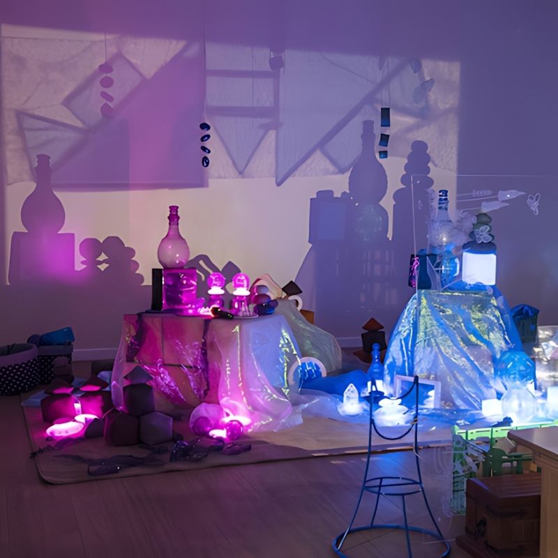 TTS Early Years Projector creating an immersive pink and purple light and shadow environment with fabric and loose materials, ideal for sensory rooms and early years imaginative play
