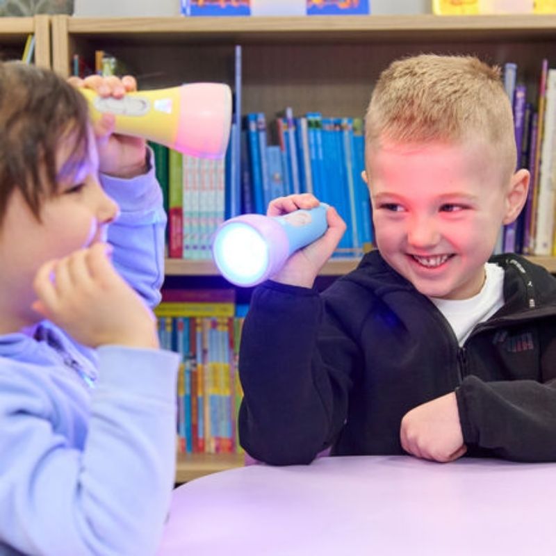 Two children using TTS Colour Changing Easi-Torches for colour mixing and sensory light exploration in a classroom setting