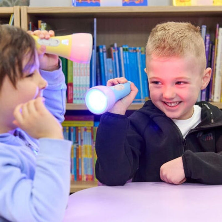 Two children using TTS Colour Changing Easi-Torches for colour mixing and sensory light exploration in a classroom setting